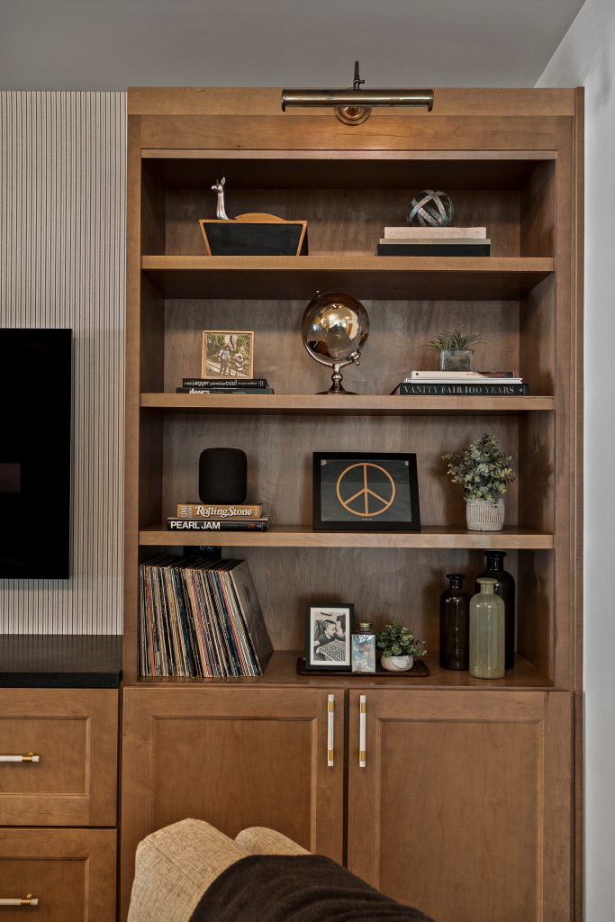 Built in oak bookcase with a brass picture light, records, and collected objects on open shelves