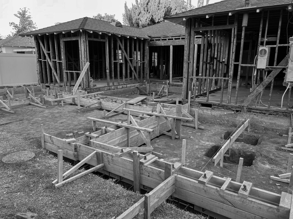 Foundation forms for the addition during construction, staked out in the yard beyond the framed house
