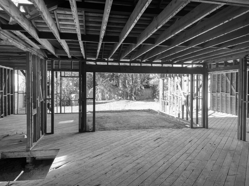 Living room during construction, framed and open to the backyard with exposed ceiling joists overhead