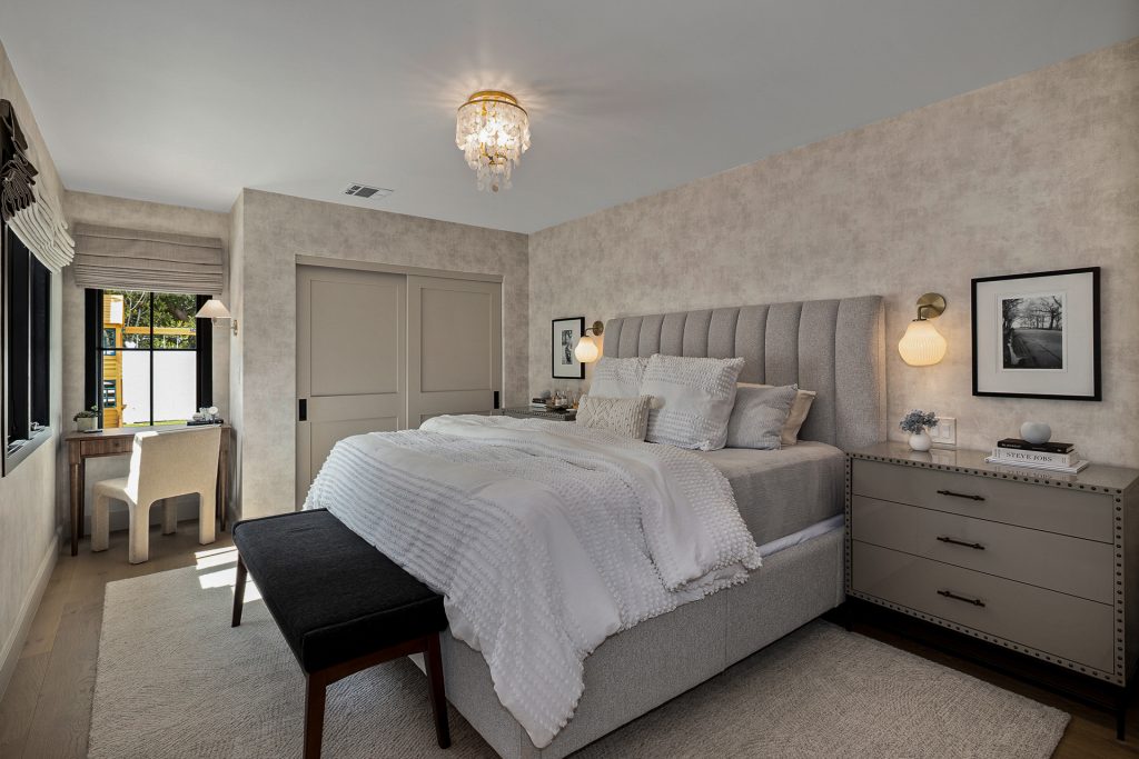 Primary bedroom with a channel tufted headboard, limewashed walls, and a small desk nook beside the window