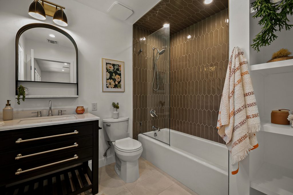 Guest bathroom with dark vanity, patterned tile, and warm lighting