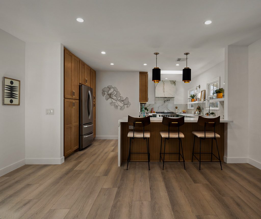 Wide view of the renovated kitchen with dark green cabinetry, open shelving, and a window over the sink