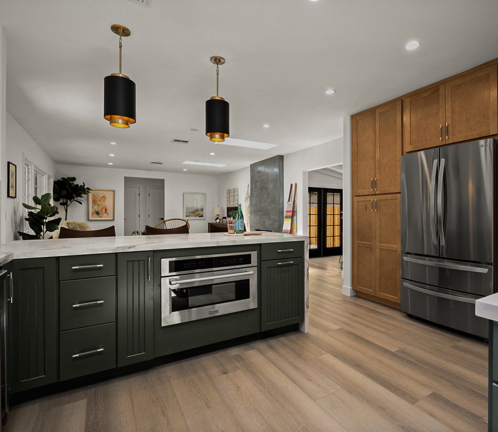 Kitchen island with dark green cabinetry, veined stone countertop, and pendant lighting