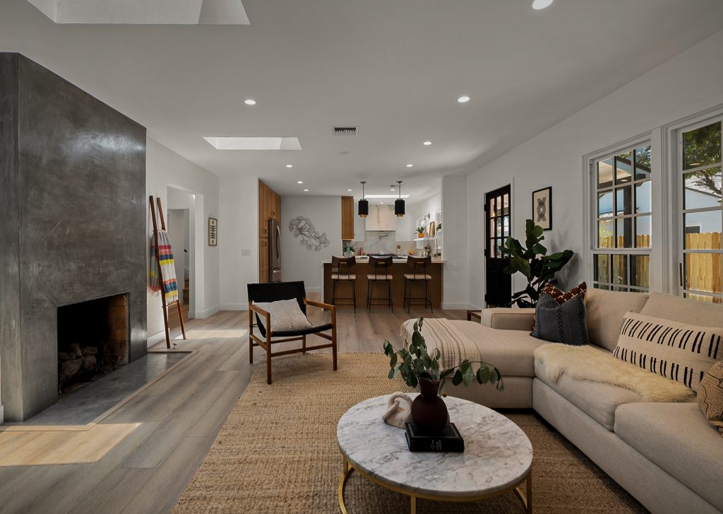 Open living room with natural light, warm wood floors, and neutral furnishings