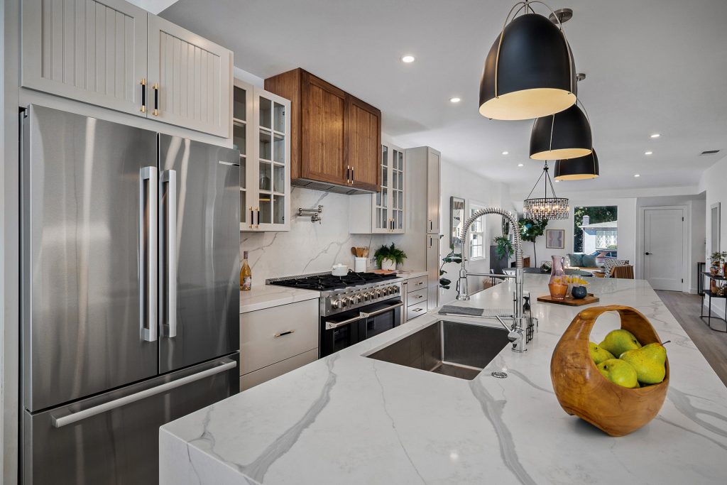 Kitchen with a waterfall marble island, panelled cabinetry, walnut upper cabinets, and a professional range