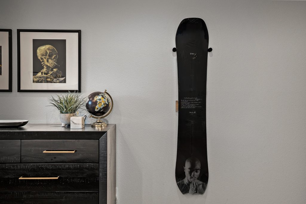 Snowboard printed with a Tupac portrait mounted as artwork above a black sideboard