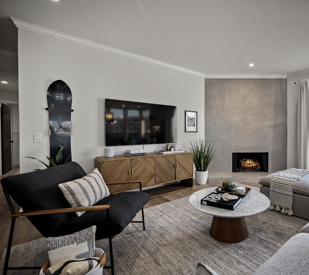 Living room television wall with a snowboard mounted alongside a chevron walnut console and a plaster fireplace
