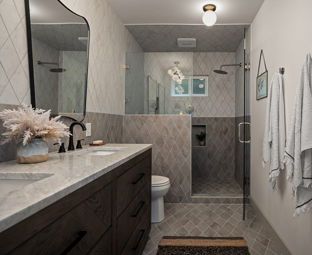 Primary bathroom in diamond tile with a glass shower, dark oak double vanity, and black fixtures