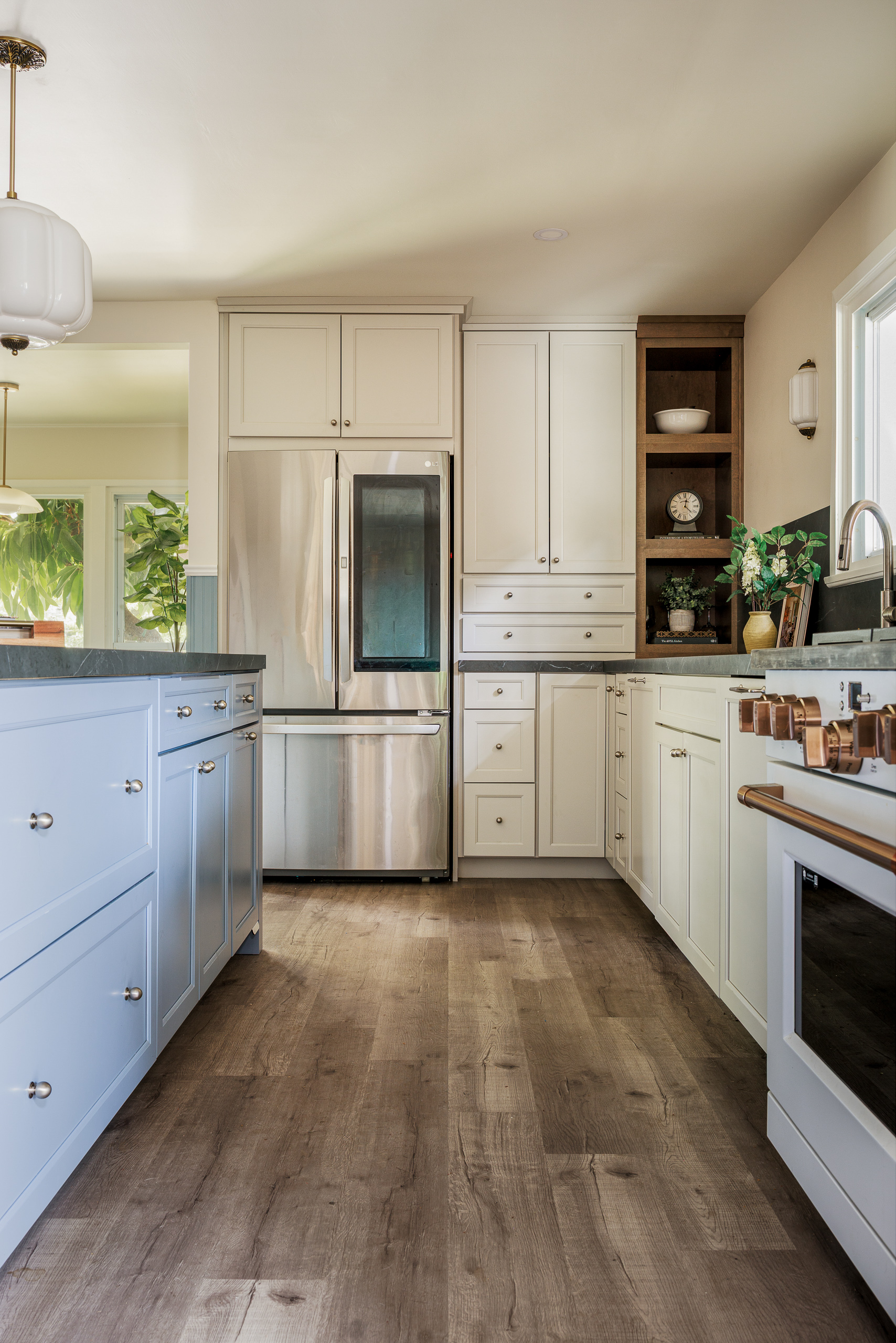 Panel run of cream cabinetry with a paneled refrigerator, open wood display shelving and wide plank oak floors