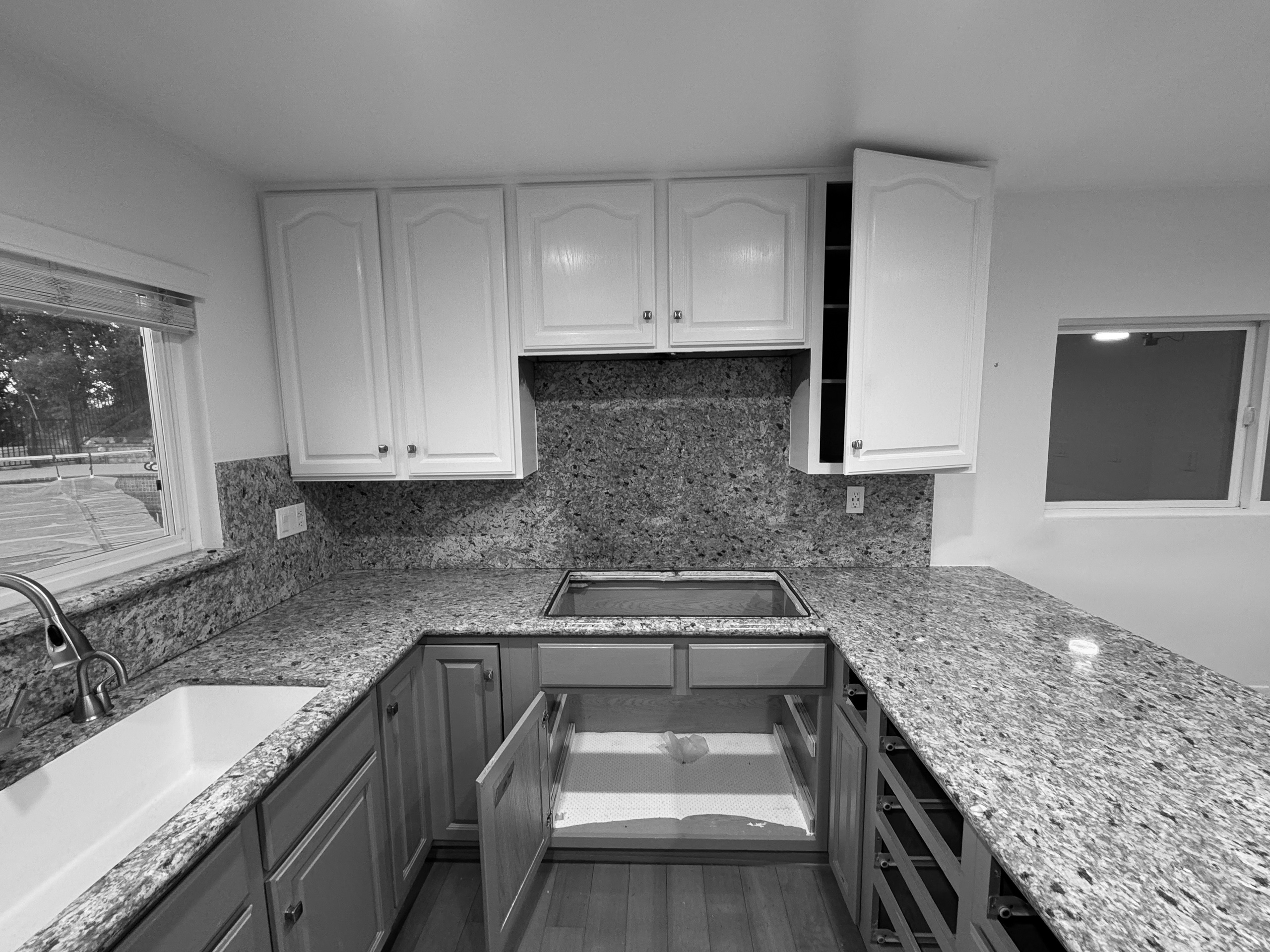The original kitchen before renovation, with cathedral-arch cabinet doors and speckled granite counters running up the wall as a backsplash